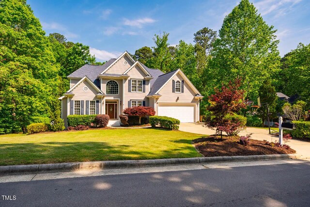 traditional-style house with concrete driveway, a garage, and a front lawn