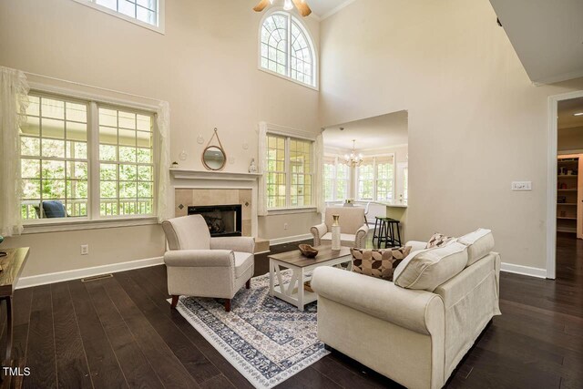 living room featuring a tiled fireplace, dark wood-type flooring, and a wealth of natural light