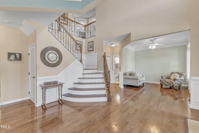 foyer entrance featuring a ceiling fan, a decorative wall, hardwood / wood-style floors, and stairway