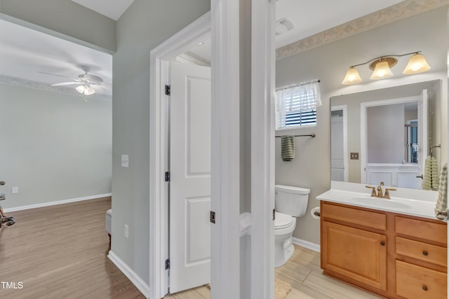 bathroom featuring ceiling fan, vanity, toilet, baseboards, and wood finished floors