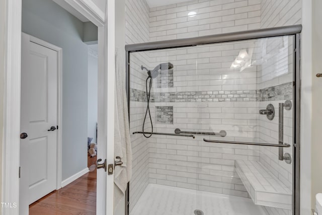 full bathroom with wood finished floors and a shower stall