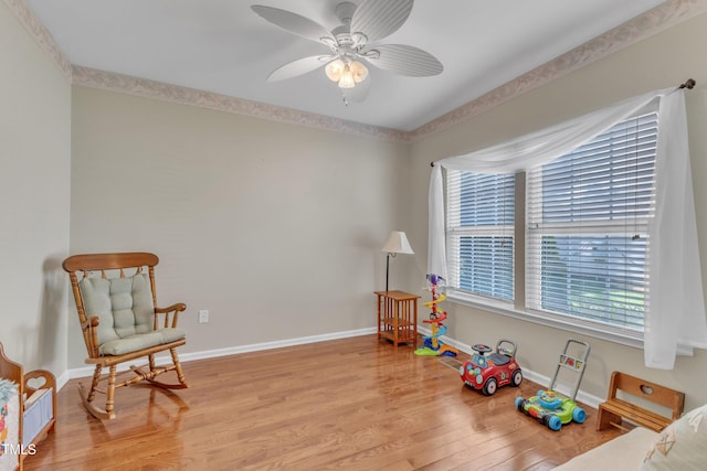 rec room featuring baseboards, ceiling fan, a healthy amount of sunlight, and light wood finished floors
