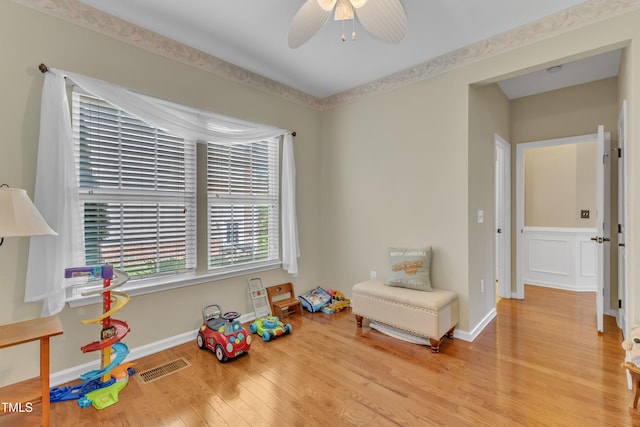 recreation room with baseboards, ceiling fan, wood finished floors, and visible vents