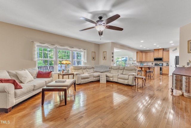 living area with light wood-type flooring, a ceiling fan, and recessed lighting