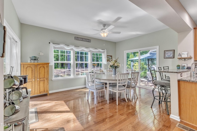 dining area with baseboards, ceiling fan, light wood finished floors, and visible vents