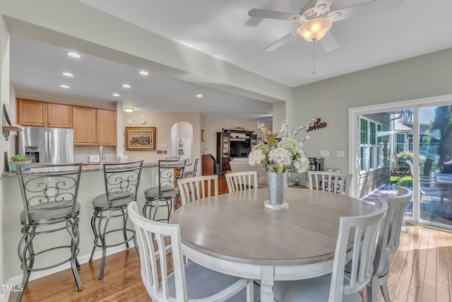 dining area with arched walkways, light wood-type flooring, a ceiling fan, and recessed lighting