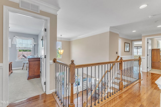 corridor featuring crown molding, baseboards, an upstairs landing, wood finished floors, and visible vents