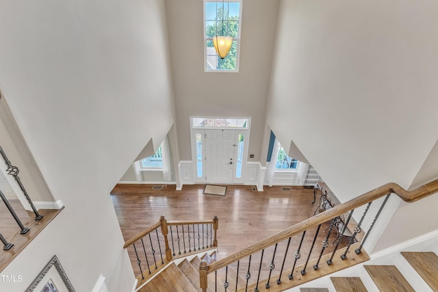 foyer featuring stairs, wood finished floors, and a towering ceiling