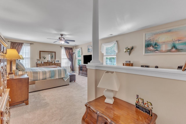 carpeted bedroom featuring visible vents, decorative columns, and ceiling fan