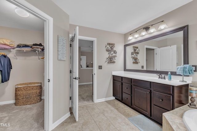 bathroom featuring baseboards, a spacious closet, tile patterned flooring, and vanity