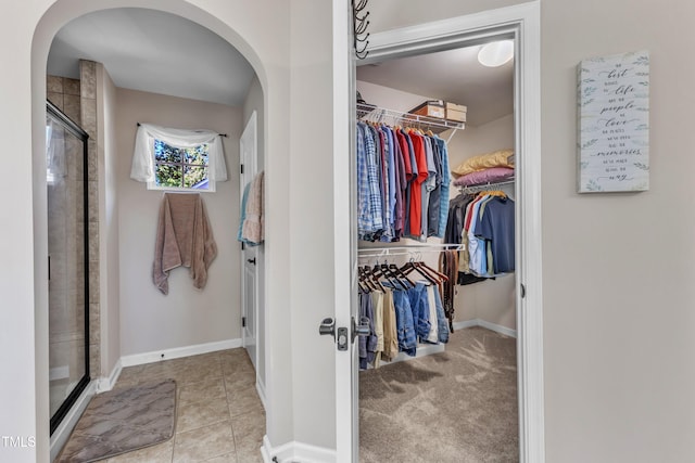 spacious closet featuring arched walkways and tile patterned flooring