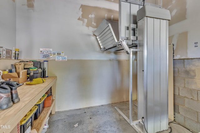 interior space featuring unfinished concrete floors, a workshop area, and concrete block wall