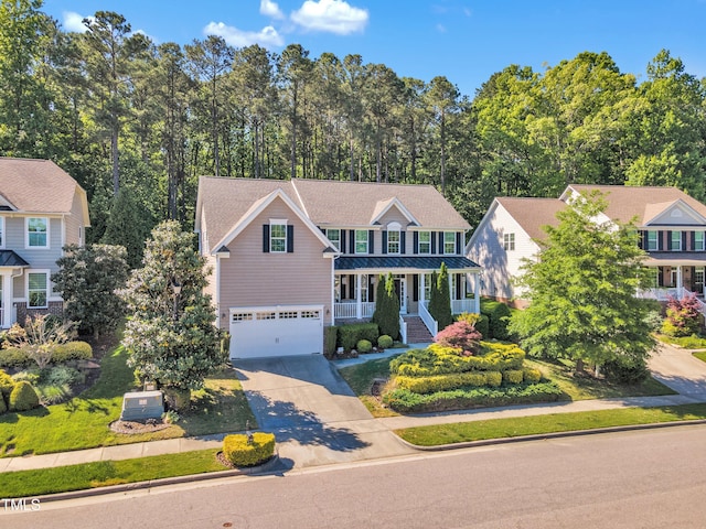 traditional home with a garage, concrete driveway, a standing seam roof, metal roof, and a porch