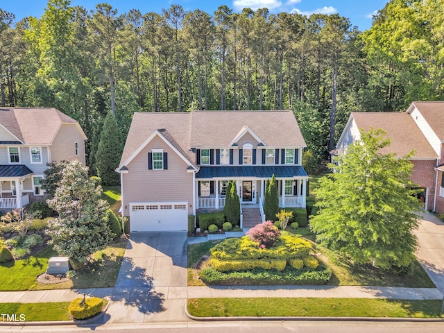 view of front of house with covered porch, a standing seam roof, metal roof, an attached garage, and driveway