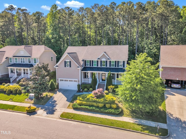 view of front of property with an attached garage, a porch, concrete driveway, a standing seam roof, and metal roof