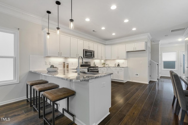 kitchen featuring crown molding, a peninsula, white cabinets, a sink, and stainless steel appliances
