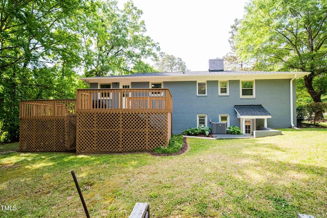 rear view of property with brick siding, a wooden deck, a chimney, cooling unit, and a yard