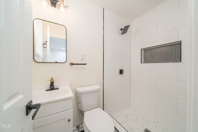 full bath with vanity, a tile shower, and toilet