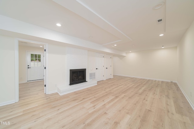 unfurnished living room featuring baseboards, recessed lighting, light wood finished floors, and a brick fireplace