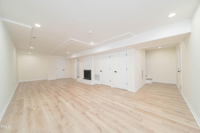 unfurnished living room with recessed lighting, baseboards, light wood-style flooring, and a fireplace