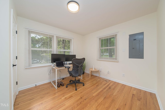 office area with baseboards, visible vents, wood finished floors, and electric panel