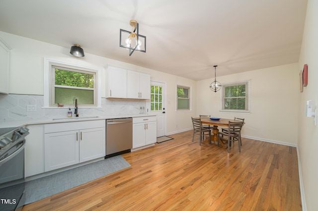 kitchen with decorative backsplash, light countertops, a sink, light wood finished floors, and stainless steel appliances