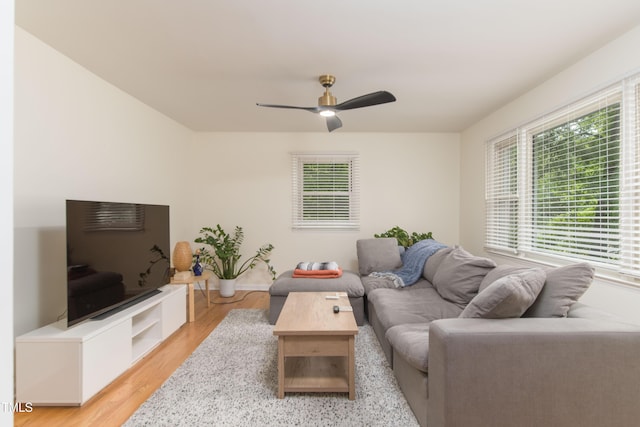 living room with baseboards, a ceiling fan, and light wood finished floors