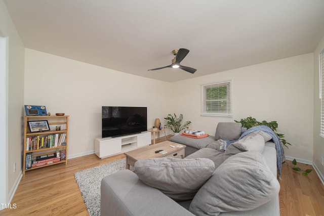 living room featuring baseboards, a ceiling fan, and light wood finished floors