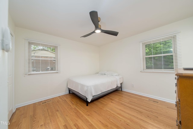 bedroom featuring baseboards, visible vents, multiple windows, and light wood finished floors