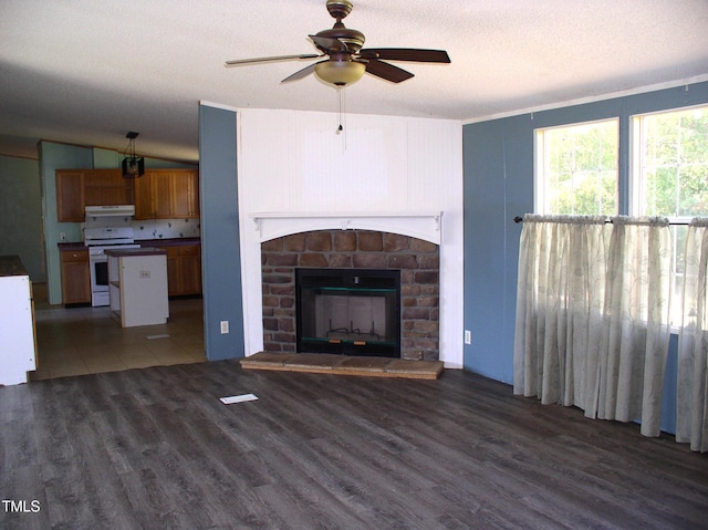 unfurnished living room with a textured ceiling, a fireplace, a ceiling fan, and wood finished floors