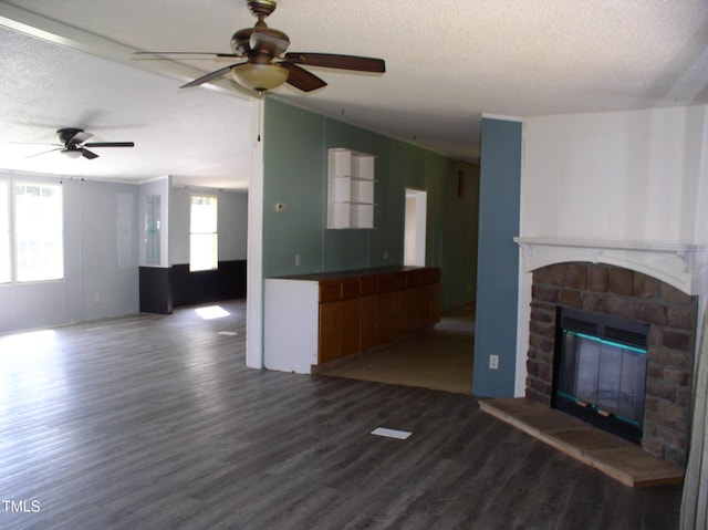 unfurnished living room with a textured ceiling, ceiling fan, wood finished floors, and a fireplace