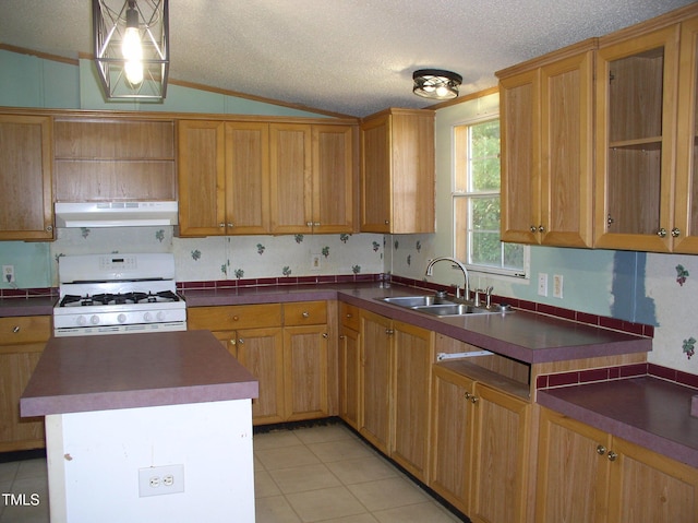 kitchen with dark countertops, a sink, ventilation hood, gas range gas stove, and lofted ceiling