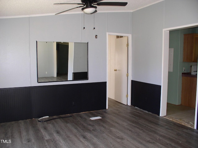 empty room featuring a textured ceiling, ceiling fan, wood finished floors, and a wainscoted wall