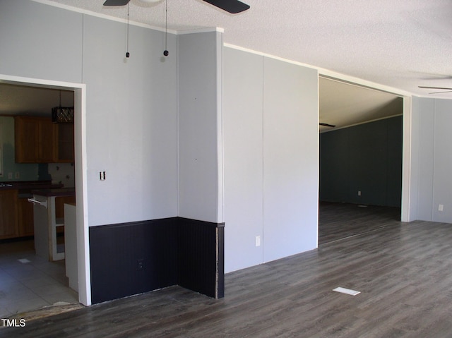 interior space with a textured ceiling, ceiling fan, ornamental molding, and wood finished floors