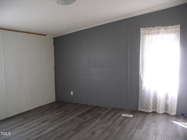 unfurnished room featuring crown molding, a textured ceiling, wood finished floors, and visible vents