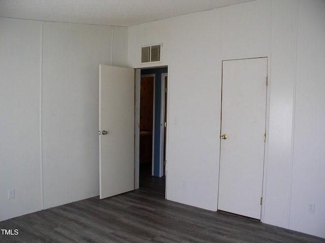 unfurnished bedroom featuring visible vents and dark wood-style flooring