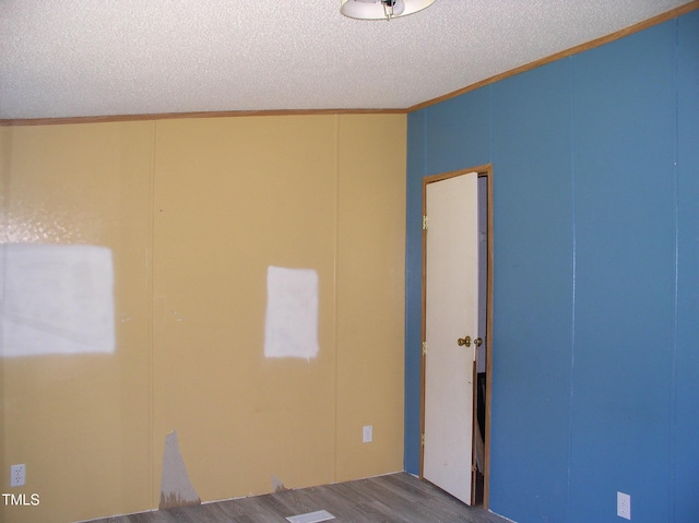 unfurnished room featuring ornamental molding, a decorative wall, dark wood-style flooring, and a textured ceiling