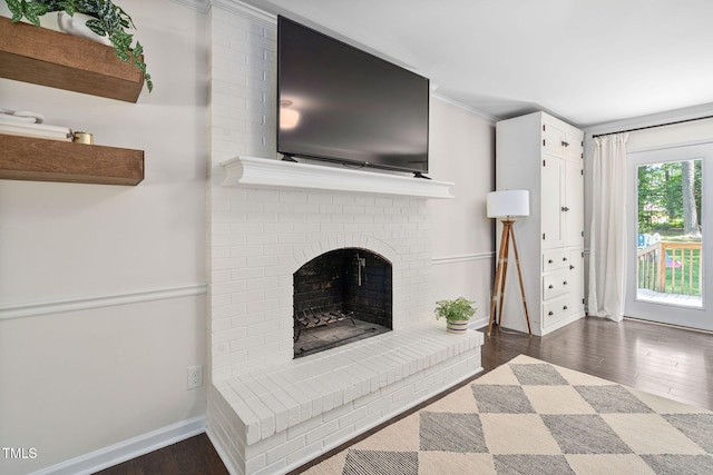 living room featuring dark wood-style flooring, baseboards, ornamental molding, and a fireplace