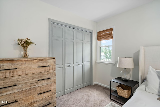 bedroom featuring baseboards, a closet, and light colored carpet
