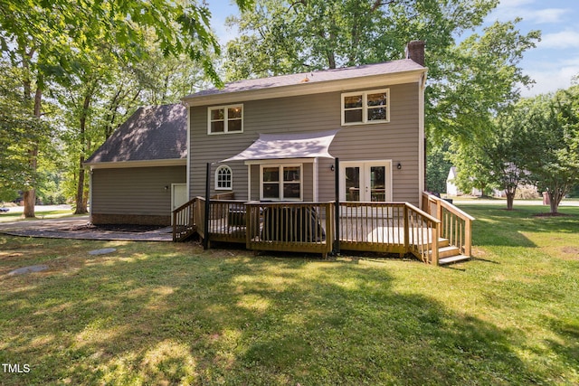back of property featuring roof with shingles, french doors, a deck, a chimney, and a lawn