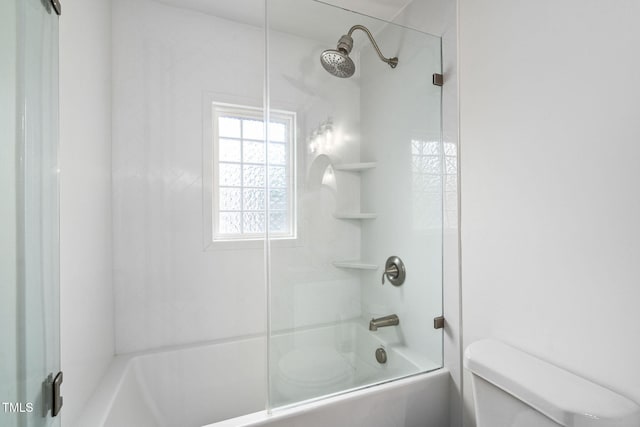 bathroom with bath / shower combo with glass door and toilet
