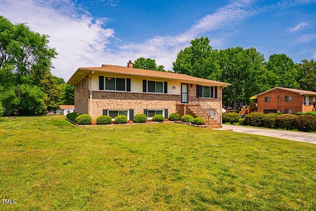 view of front facade featuring a chimney, a front yard, driveway, and brick siding