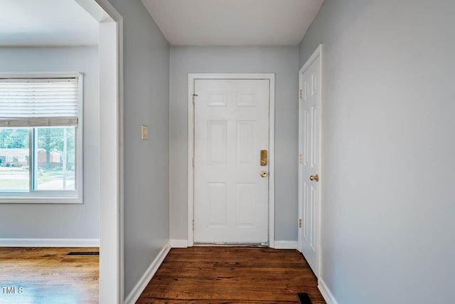 doorway to outside with baseboards and dark wood-type flooring