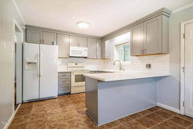kitchen featuring a sink, white appliances, a peninsula, decorative backsplash, and gray cabinetry