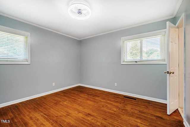 unfurnished room featuring crown molding, baseboards, wood finished floors, and visible vents