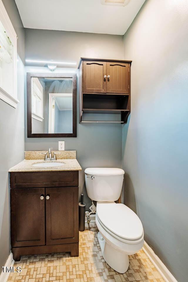 bathroom with baseboards, toilet, and vanity