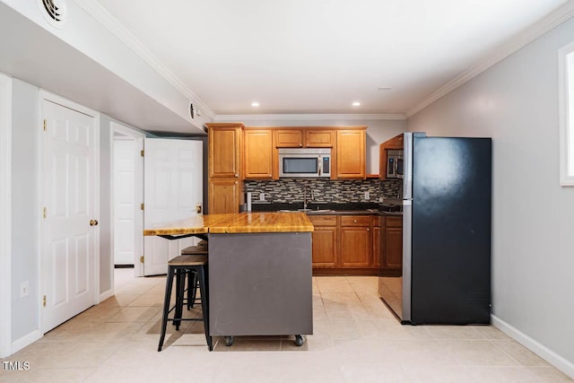 kitchen featuring decorative backsplash, a center island, baseboards, a breakfast bar, and stainless steel appliances