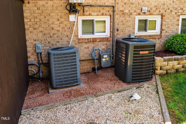details with brick siding, central AC unit, and gas meter