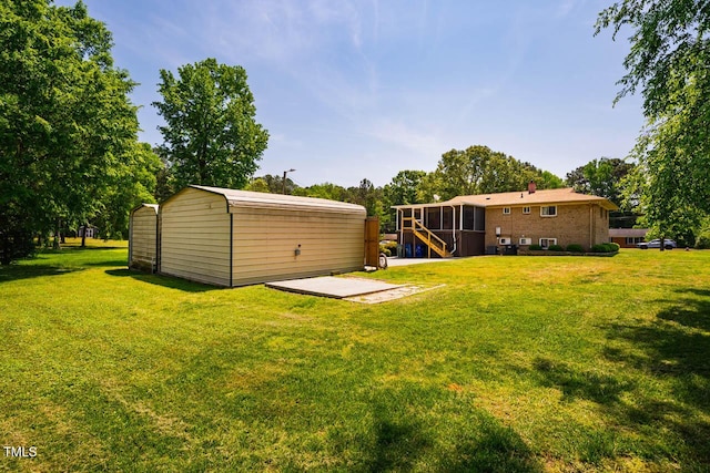 view of yard with an outdoor structure, a sunroom, and a patio area