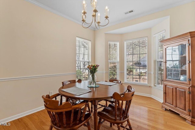 dining space with crown molding, light wood finished floors, a chandelier, baseboards, and visible vents